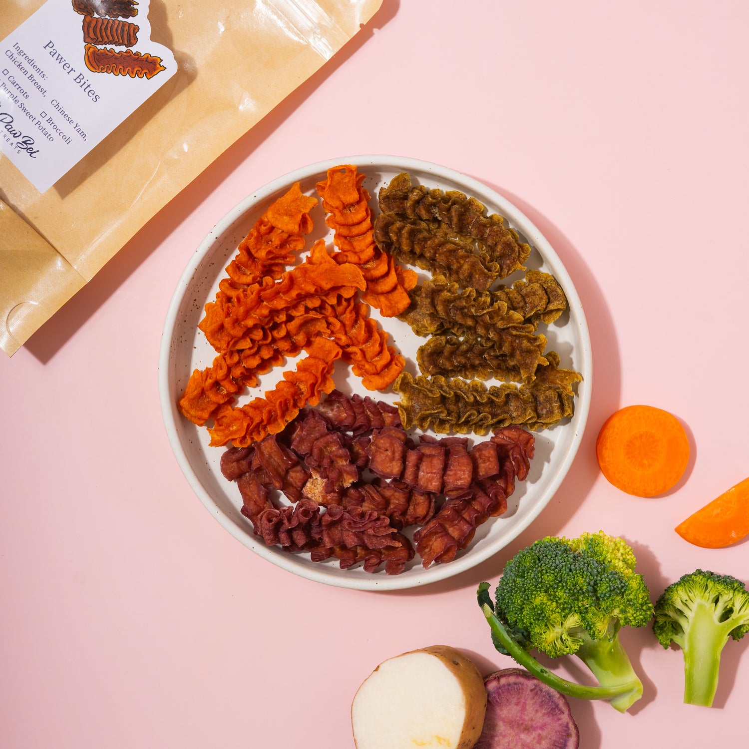 Assorted pet treats on a plate with a pink background