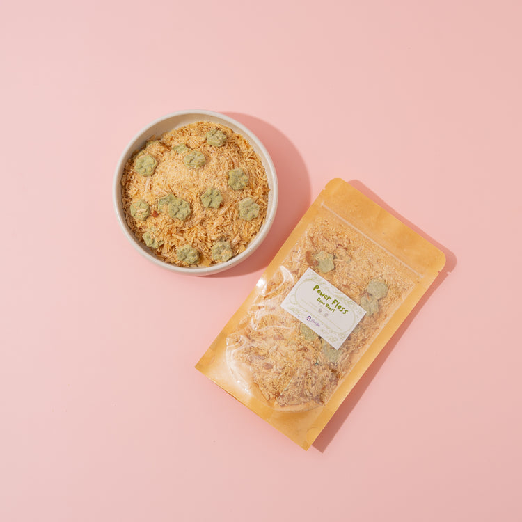 Bowl and package of pet food with visible brand label on a pink background