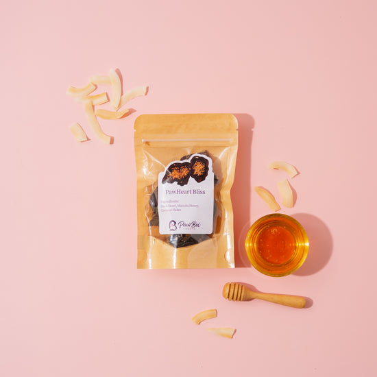 Packaged product with a label on a pink background, surrounded by dried fruit pieces and a small bowl of honey.
