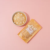 Packaged food item with a bowl of granola on a pink background